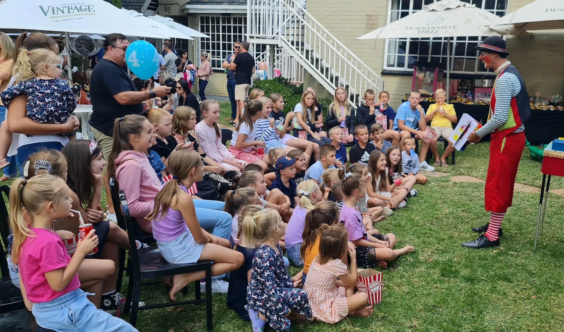 CJ the Clown performing his magic show to a crowd of children at a garden venue